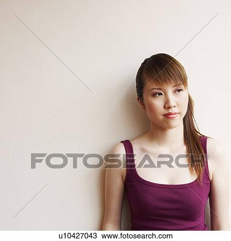 Stock Image - Young woman leaning against a wall. Fotosearch