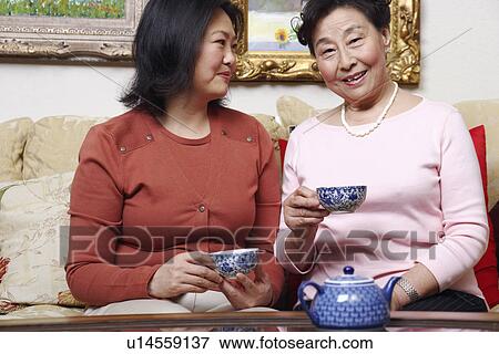 Stock Photo - Close-up of a mother and her daughter holding tea cups. Fotosearch