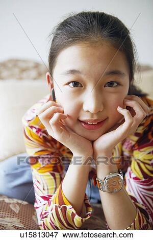 Stock Photo - Close-up of a young woman with her hands on her chin. Fotosearch