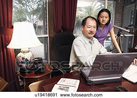Stock Image - Father and his daughter looking at a laptop. Fotosearch