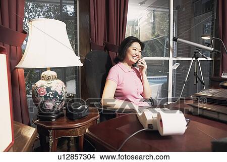 Picture - Mature woman talking on a cordless telephone. Fotosearch