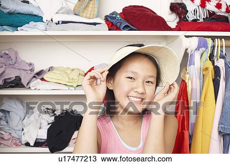 Stock Image - Portrait of a girl holding a hat on her head. Fotosearch