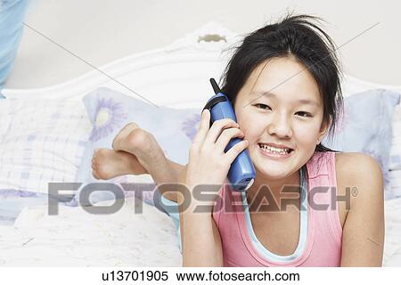 Stock Photography - Portrait of a girl using a cordless telephone. Fotosearch