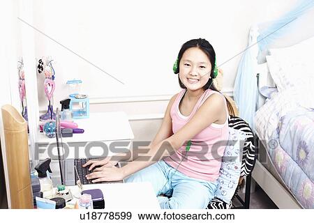 Stock Photo - Portrait of a girl using a laptop and listening to music. Fotosearch