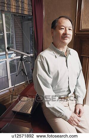 Stock Image - Portrait of a senior man sitting in an office. Fotosearch