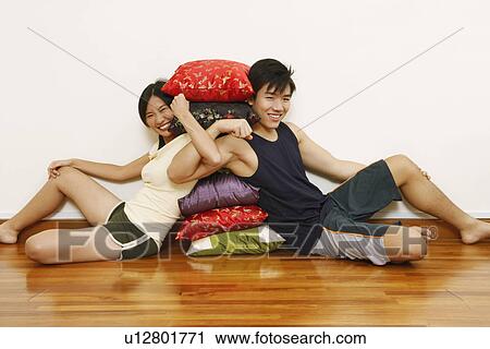 Portrait of a young couple sitting and leaning against a stack of cushions View Large Photo Image Stock Image - Portrait of a young couple sitting and leaning against a stack of cushions. Fotosearch