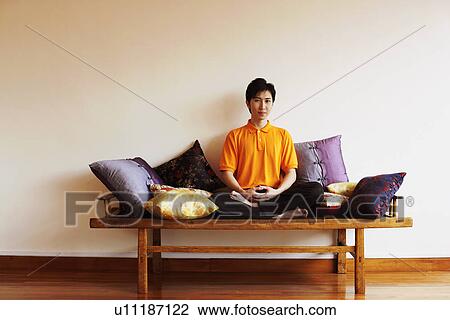 Stock Image - Portrait of a young man sitting on a bench. Fotosearch