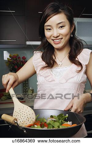 Portrait of a young woman cooking View Large Photo Image Stock Photo - Portrait of a young woman cooking. Fotosearch