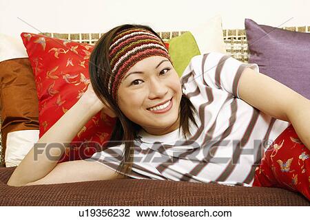 Portrait of a young woman lying on a couch and smiling View Large Photo Image Stock Image - Portrait of a young woman lying on a couch and smiling. Fotosearch