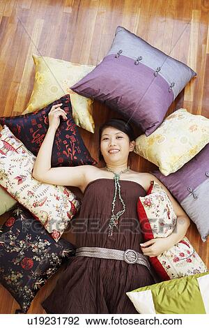 Stock Image - Portrait of a young woman smiling and lying on a hardwood floor. Fotosearch