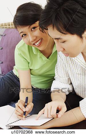 Portrait of a young woman writing in a diary and a young man beside her View Large Photo Image Stock Photo - Portrait of a young woman writing in a diary and a young man beside her. Fotosearch
