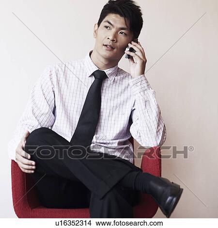 Businessman sitting in an armchair and talking on a mobile phone View Large Photo Image Picture - Businessman sitting in an armchair and talking on a mobile phone. Fotosearch