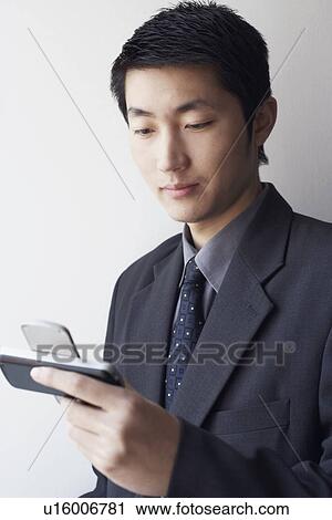 Stock Image - Close-up of a businessman looking at a mobile phone. Fotosearch