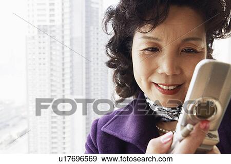 Close-up of a businesswoman operating a mobile phone smiling View Large Photo Image Stock Photo - Close-up of a businesswoman operating a mobile phone smiling. Fotosearch