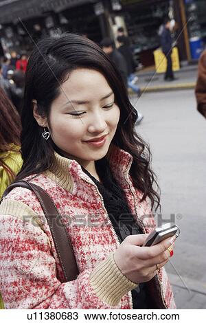 Stock Image - Close-up of a young woman holding a mobile phone. Fotosearch