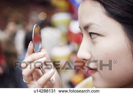 Close-up of a young woman looking into a vanity mirror View Large Photo Image Stock Image - Close-up of a young woman looking into a vanity mirror. Fotosearch