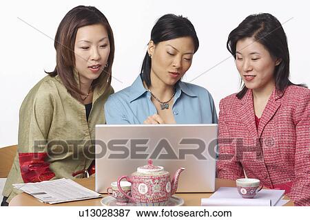 Stock Photo - Close-up of three businesswomen in front of a laptop. Fotosearch