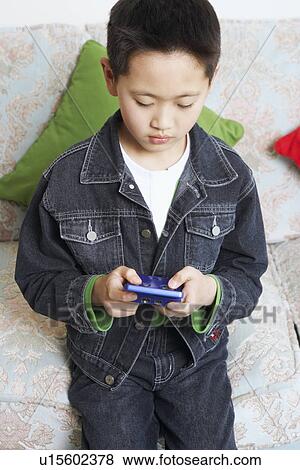 Stock Photo - High angle view of a boy playing a video game. Fotosearch