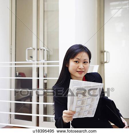 Stock Photography - Portrait of a businesswoman holding a newspaper and smiling. Fotosearch