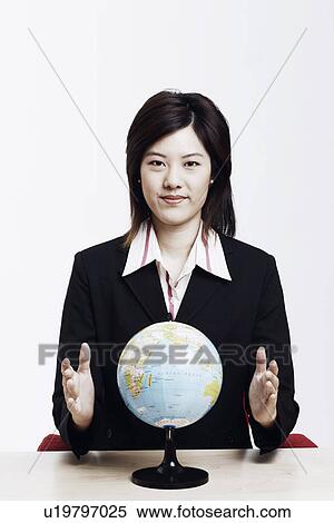 Portrait of a businesswoman sitting with a globe in front of him View Large Photo Image Stock Photography - Portrait of a businesswoman sitting with a globe in front of him. Fotosearch