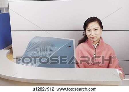 Stock Image - Portrait of a mature woman sitting in an office. Fotosearch