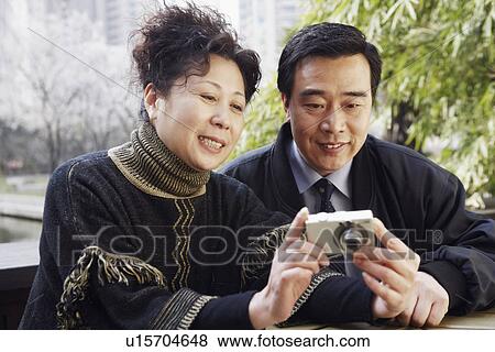 Stock Photo - Close-up of a mature couple looking at a digital camera smiling. Fotosearch