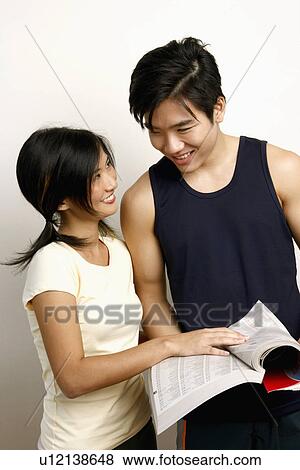 Close-up of a young couple holding a directory and looking at each other View Large Photo Image Stock Photo - Close-up of a young couple holding a directory and looking at each other. Fotosearch