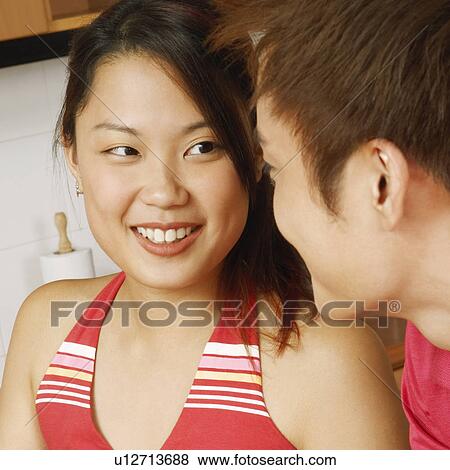 Stock Photo - Close-up of a young couple looking at each other at a kitchen counter. Fotosearch