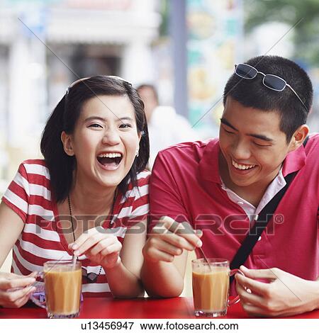 Stock Photo - Close-up of a young couple sitting on the sidewalk cafe and smiling. Fotosearch