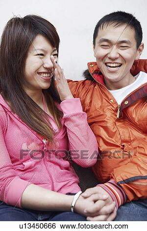 Stock Photograph - Close-up of a young couple sitting together smiling. Fotosearch