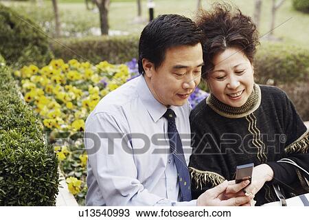 Mature couple looking at a mobile phone smiling View Large Photo Image Stock Image - Mature couple looking at a mobile phone smiling. Fotosearch