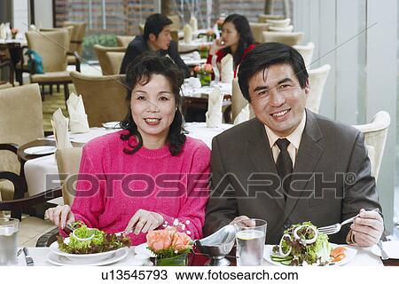 Stock Image - Portrait of a mature couple sitting in a restaurant smiling. Fotosearch