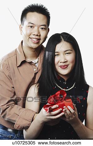 Portrait of a young couple holding a gift View Large Photo Image Stock Photography - Portrait of a young couple holding a gift. Fotosearch