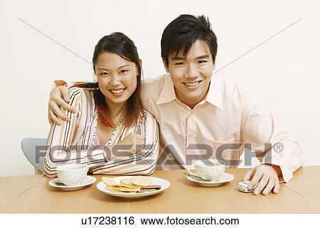Stock Photograph - Portrait of a young couple sitting together and smiling. Fotosearch