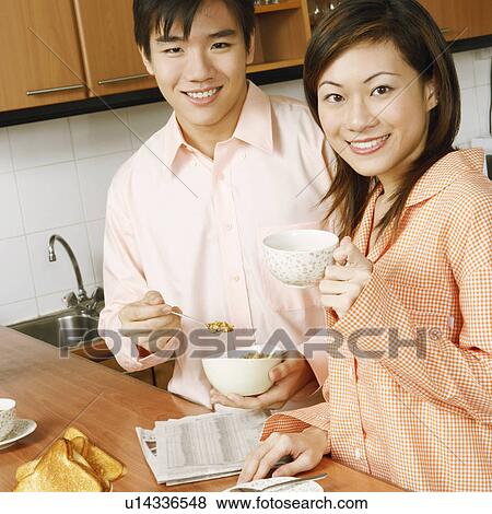 Stock Photo - Portrait of a young couple smiling at a kitchen counter. Fotosearch