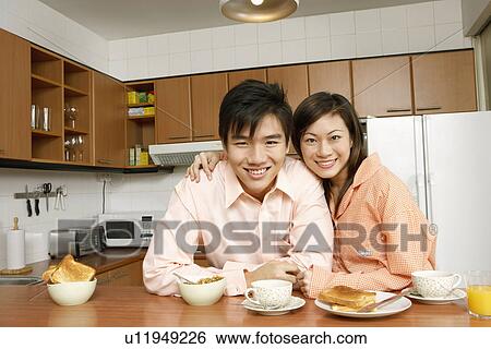 Stock Photograph - Portrait of a young couple smiling at a kitchen counter. Fotosearch