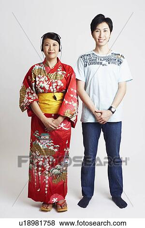 Stock Photo - Portrait of a young woman wearing headphones and a young man beside her. Fotosearch