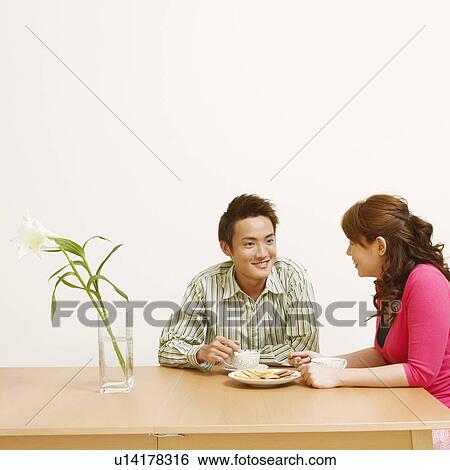 Stock Photograph - Young couple sitting on chairs and looking at each other. Fotosearch
