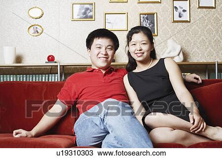 Portrait of a young couple sitting on a couch smiling View Large Photo Image Stock Image - Portrait of a young couple sitting on a couch smiling. Fotosearch