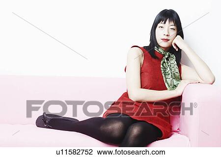 Portrait of a young woman leaning on a couch View Large Photo Image Stock Image - Portrait of a young woman leaning on a couch. Fotosearch