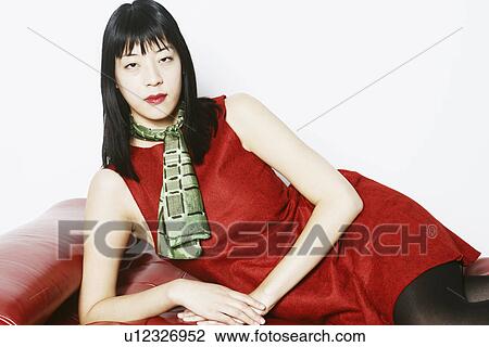 Stock Image - Portrait of a young woman lying on a mattress. Fotosearch