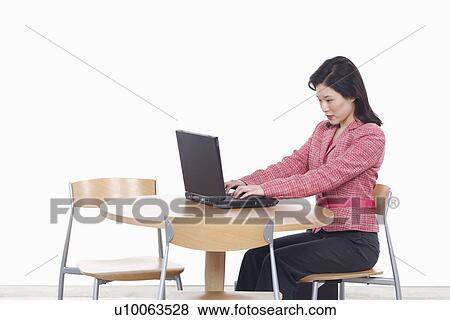 Stock Photo - Side profile of a businesswoman using a laptop. Fotosearch
