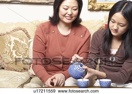 Stock Photo - Close-up of a girl pouring tea for her mother. Fotosearch