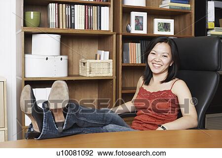 Portrait of a businesswoman sitting with her legs on the table View Large Photo Image Stock Image - Portrait of a businesswoman sitting with her legs on the table. Fotosearch