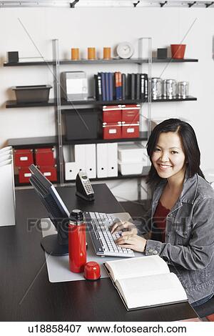 Stock Photo - Portrait of a businesswoman using a computer smiling. Fotosearch