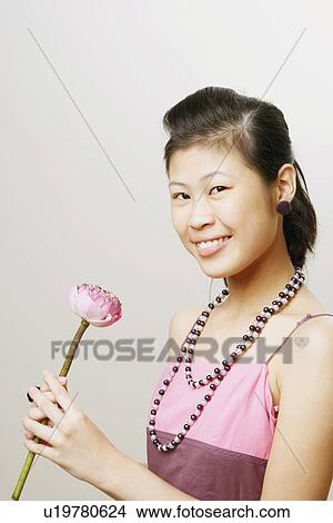 Picture - Portrait of a young woman holding a lotus flower and smiling. Fotosearch