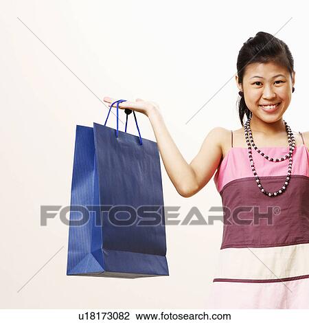 Portrait of a young woman holding shopping bags and smiling View Large Photo Image Stock Image - Portrait of a young woman holding shopping bags and smiling. Fotosearch
