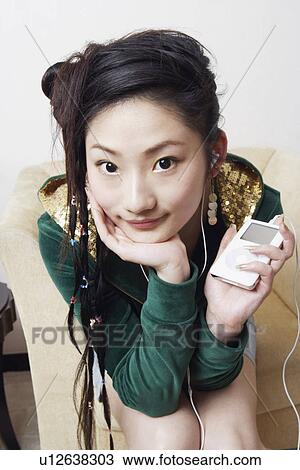 Stock Image - Portrait of a young woman listening to music. Fotosearch
