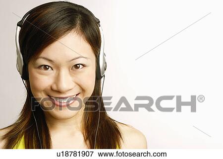 Portrait of a young woman listening to music and smiling View Large Photo Image Stock Photo - Portrait of a young woman listening to music and smiling. Fotosearch