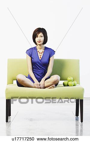 Portrait of a young woman sitting on a couch View Large Photo Image Stock Image - Portrait of a young woman sitting on a couch. Fotosearch